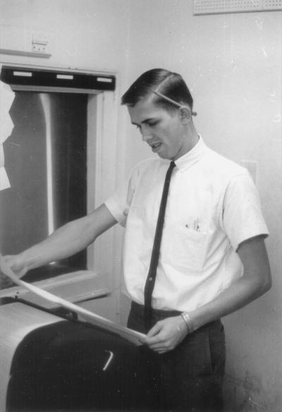 Young man reading newswire teletype print out