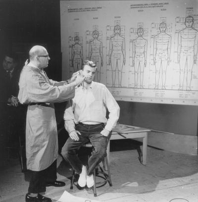 Dr. Charles Snow measuring students head during taping of televised anthropology course