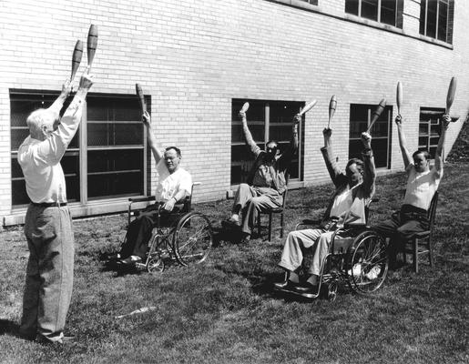 A group of patients on the grounds of a rehabilitation hospital (Cardinal Hill?) exercising with an instructor