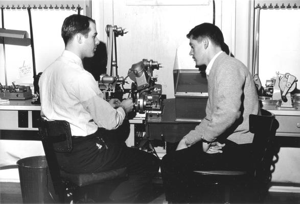 Two men working with film editing equipment