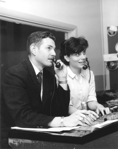 Two persons in master control, using headsets to communicate with studio personnel