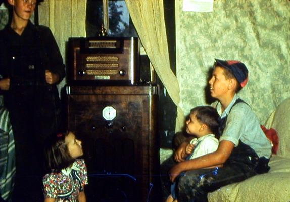 Man and children sitting around radio