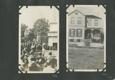 men in uniform standing in the road with people watching on the sides appears to be a parade; a man standing on the porch of a house