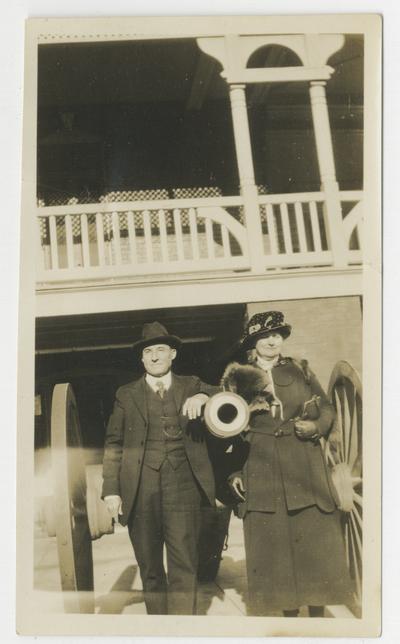 Unidentified man and woman standing on either side of the barrel of a cannon