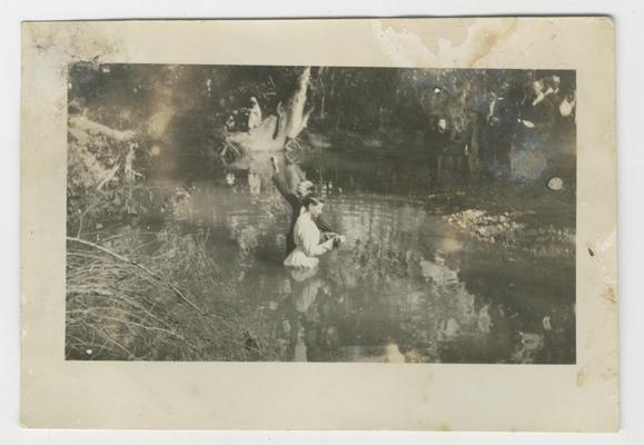 Unidentified man baptizing an unidentified woman in a stream