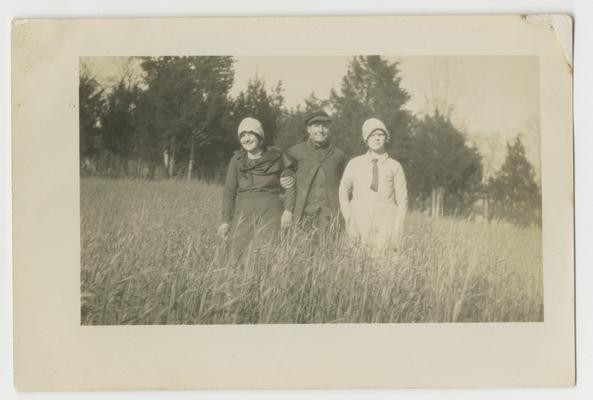 Unidentified man and two women in a field