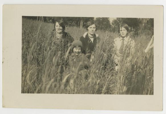 Three unidentified young women and a child in a field