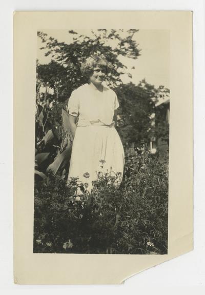 Unidentified young woman standing in garden