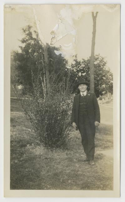 Unidentified man next to a large bush