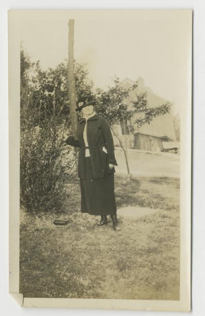 Unidentified woman next to a large bush