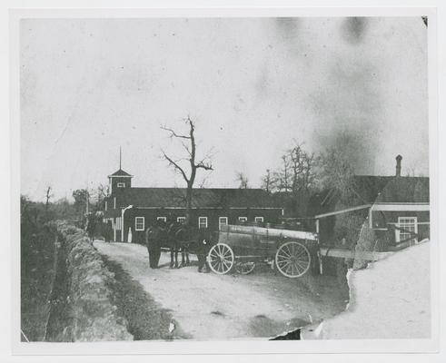 Man with mule and wagon backed up to a loading dock