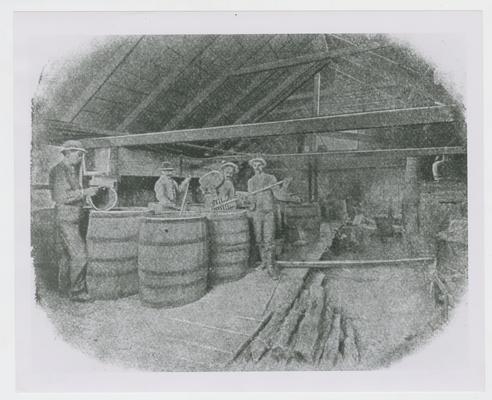 Four men mixing mash in barrels, photographic reproduction