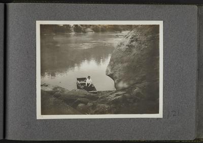 Woman in wooden boat on shore of river