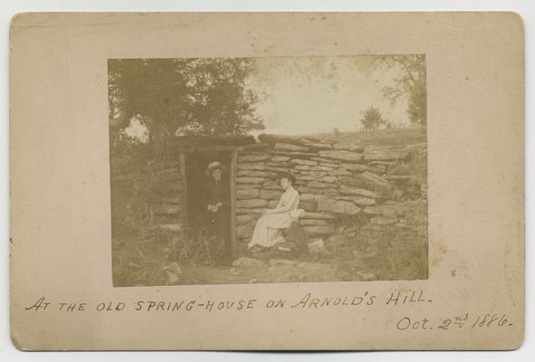 Natural rock fence with two women; At the old spring-house on Arnold's Hill Oct 2nd, 1886 written on front in ink
