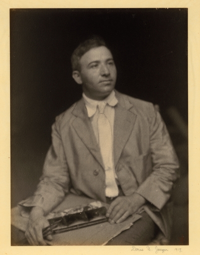 Man in coat and tie, seated with art supplies