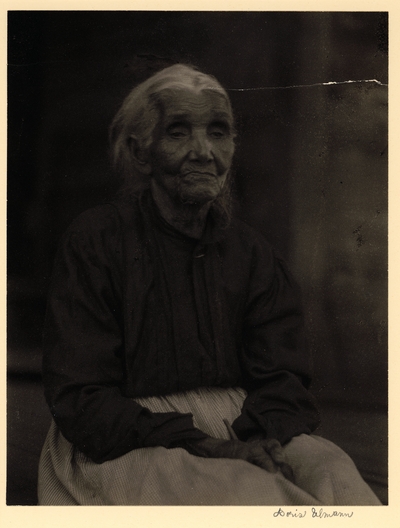 Elderly black woman in blouse and skirt, seated