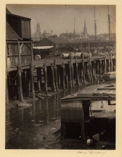 Wharf at low tide with boats docked in foreground and town in background