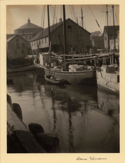 Boats in harbor with wharf and buildings in background