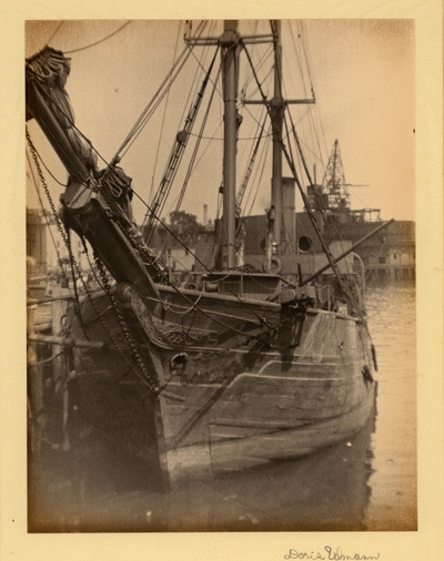 Head-on view of ship with carvings on the front in harbor