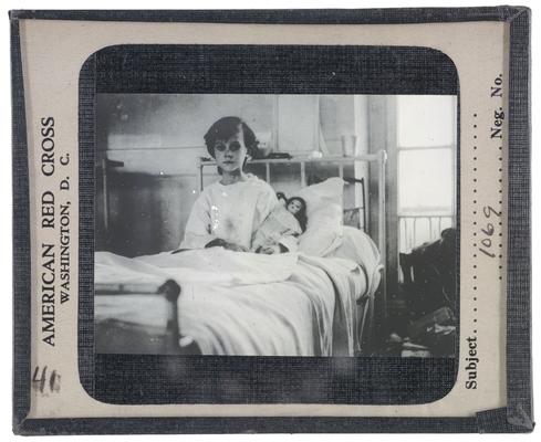 Unidentified female patient in a hospital bed; American Red Cross slide