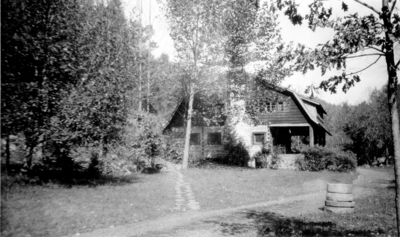 Log Cabin with clapboard addition surrounded by woods.  On backside of photograph handwritten 
