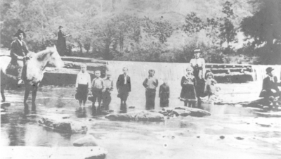 Unidentified people in a creek below a water fall. Silver Print