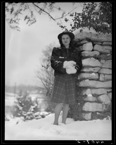 Campus views (1940 Kentuckian) (University of Kentucky); woman                             standing next to stone (rock) wall