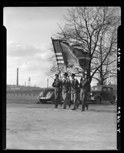 Military Color Guard (1940 Kentuckian) (University of Kentucky);                             four member in uniform marching in a parade, two members holding                             flags