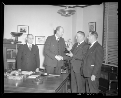 Kentucky Utilities Company (167 West Main Street); interior of                             office, group of men gathered around a desk, man is receiving a trophy                             and accepting congratulatory handshake