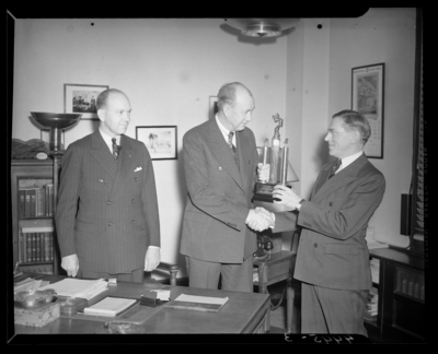 Kentucky Utilities Company (167 West Main Street); interior of                             office, group of men gathered around a desk, man is receiving a trophy                             and accepting congratulatory handshake