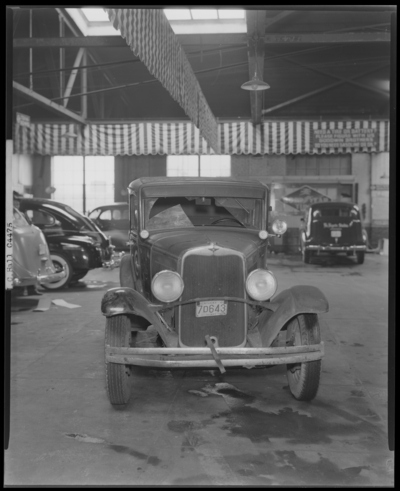 Mr. J.C. Hall; damaged car (automobile) parked inside of garage                             (service garage), front view of vehicle; Kentucky License plate number                             7D643 Henry County (KY License plate no. 7D643)