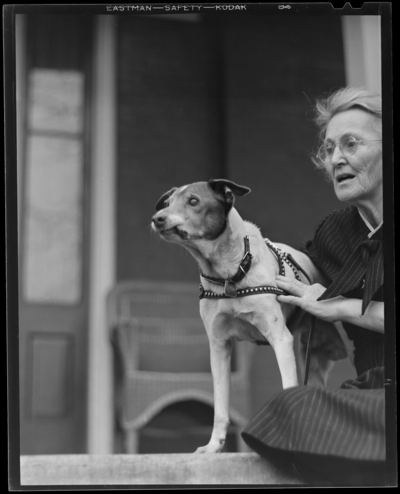 Mrs. March & dog (age 14); dog standing on table, woman                             holding dog by collar
