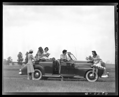 Loom & Needle, 170 Esplanade (clothing); models for                             advertisement, models gathered around a car parked in a                             field