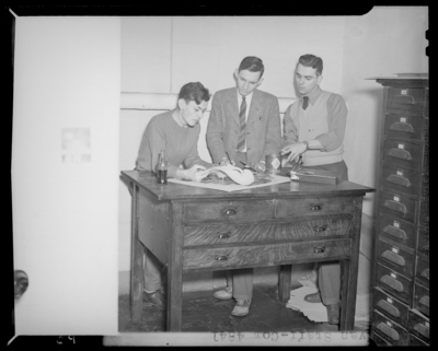 Kentuckian Staff & Press Room, (1942 Kentuckian)                             (University of Kentucky); McVey Hall, basement; three workers gathered                             around a table