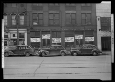 E.L. Martin Wholesale Grocers, 414-416 West Main; exterior view                             of building and window displays, cars parked in front of                             building