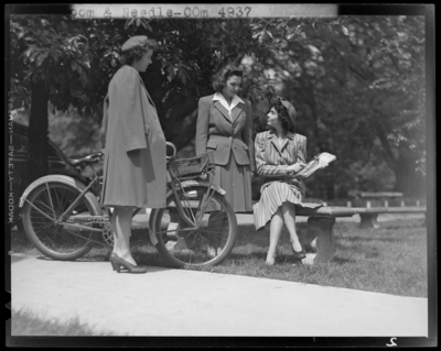 Loom & Needle (clothing retailer); outdoors; three women                             gathered around a park bench and bicycle