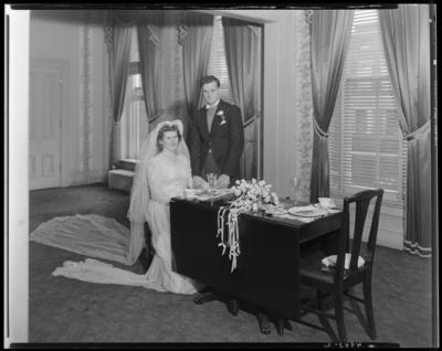 Mr. & Mrs. Jay Richard Miller Jr.; wedding; bride sitting                             at table, groom standing beside bride