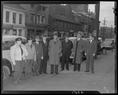 Lexington Yellow Cab, 150 North Limestone; group for first women                             drivers; two women drivers in uniform standing with a group of men in                             front of cab cars; Walnut Street & unidentified cross street;                             sign for Wombell's Automotive Parts can be seen