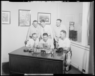 Trophy for American Legion Team; men reading 