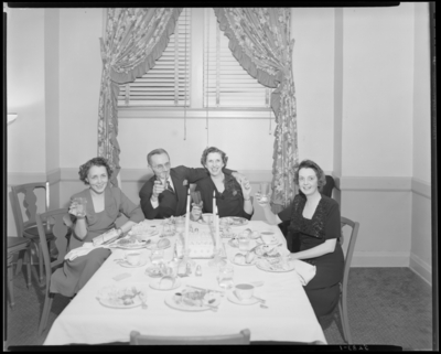 Dinner Party; Coral Room, Lafayette Hotel; interior; 3 women and                             a man sitting around a table with glasses in hand (toast)