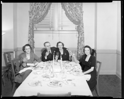 Dinner Party; Coral Room, Lafayette Hotel; interior; 3 women and                             a man sitting around a table with glasses in hand (toast)