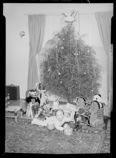 Mrs. W.E. Hupp; interior; baby sitting next to Christmas                             tree