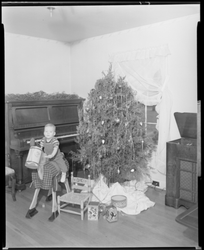 Mrs. Hughes; interior; baby sitting on toy horse next to                             Christmas tree