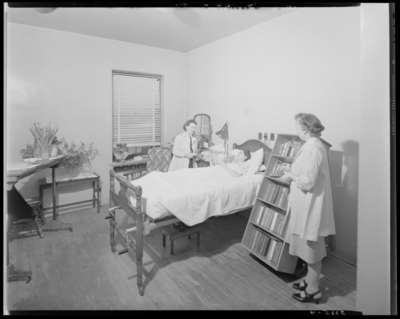 Nurse Aid; Good Samaritan Hospital, 310-330 South Limestone; aids                             with a patient; mobile book card next to bed