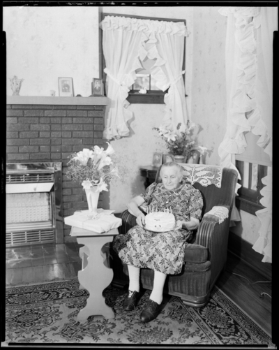 Mrs. Elizabeth Keller; (Cynthiana, Kentucky); interior; elderly                             woman sitting in a chair holding a birthday cake