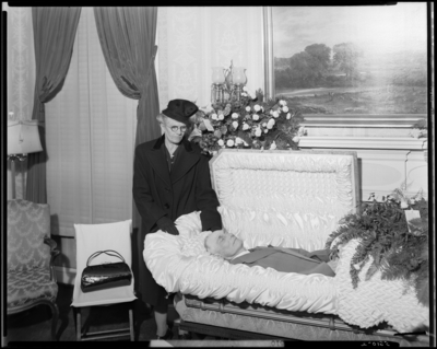 T.Z. Steward; corpse; open casket surrounded by flowers; woman                             standing next to corpse