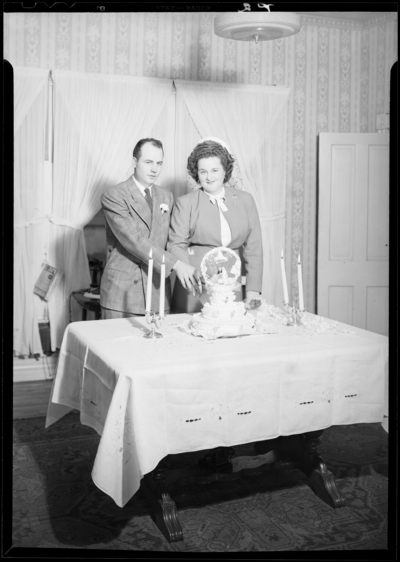 Mrs. W.E. Gwyn; wedding reception; man and woman cutting wedding                             cake