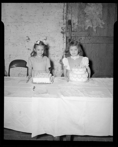 Bobby Jean Beagle; birthday party, age 6; Castlewood Barn;                             interior; two girls standing in front of two birthday cakes