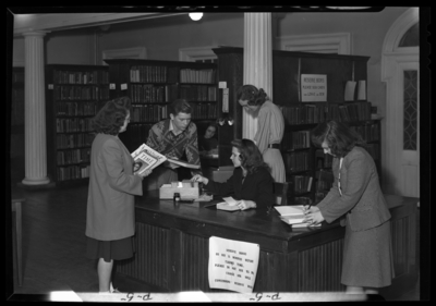Georgetown College; library; interior; students gathered around                             the check-out desk