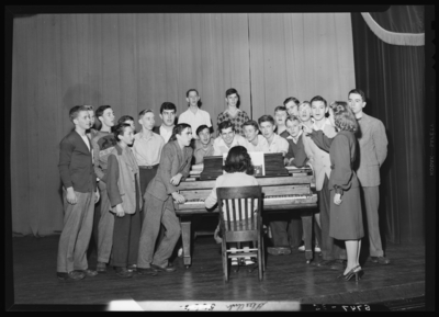 Garth High School, Georgetown; Glee Club group gathered around                             piano